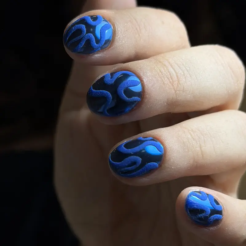 Short rounded nails with glossy cobalt-blue abstract swirl art